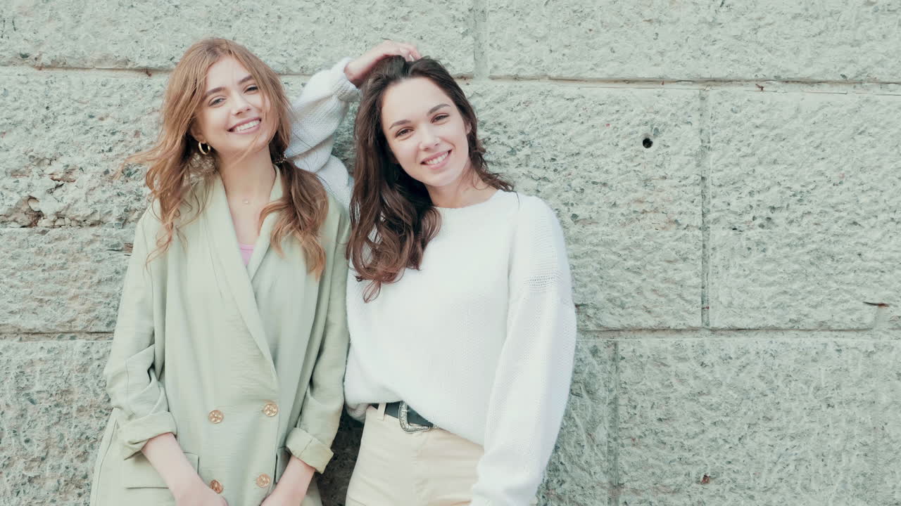 두 명의 젊은 여성이 웃으며 야외에서 포즈를 취하고 있습니다.