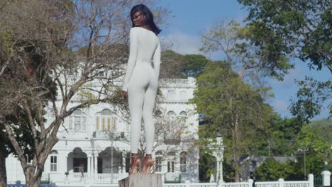 With-Whitehall-castle-in-the-background,-a-young-girl-in-a-white-bodysuit-enjoys-a-city-day-in-high-heels