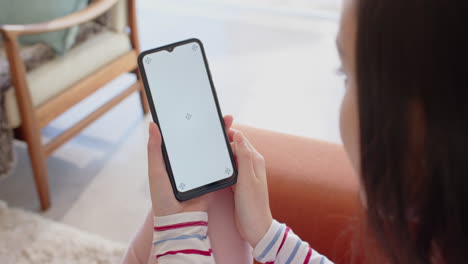 holding smartphone with blank screen, woman sitting on couch at home