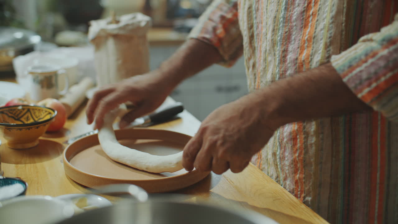 manos de un hombre rodando la masa para el pan indio en la mesa de la cocina