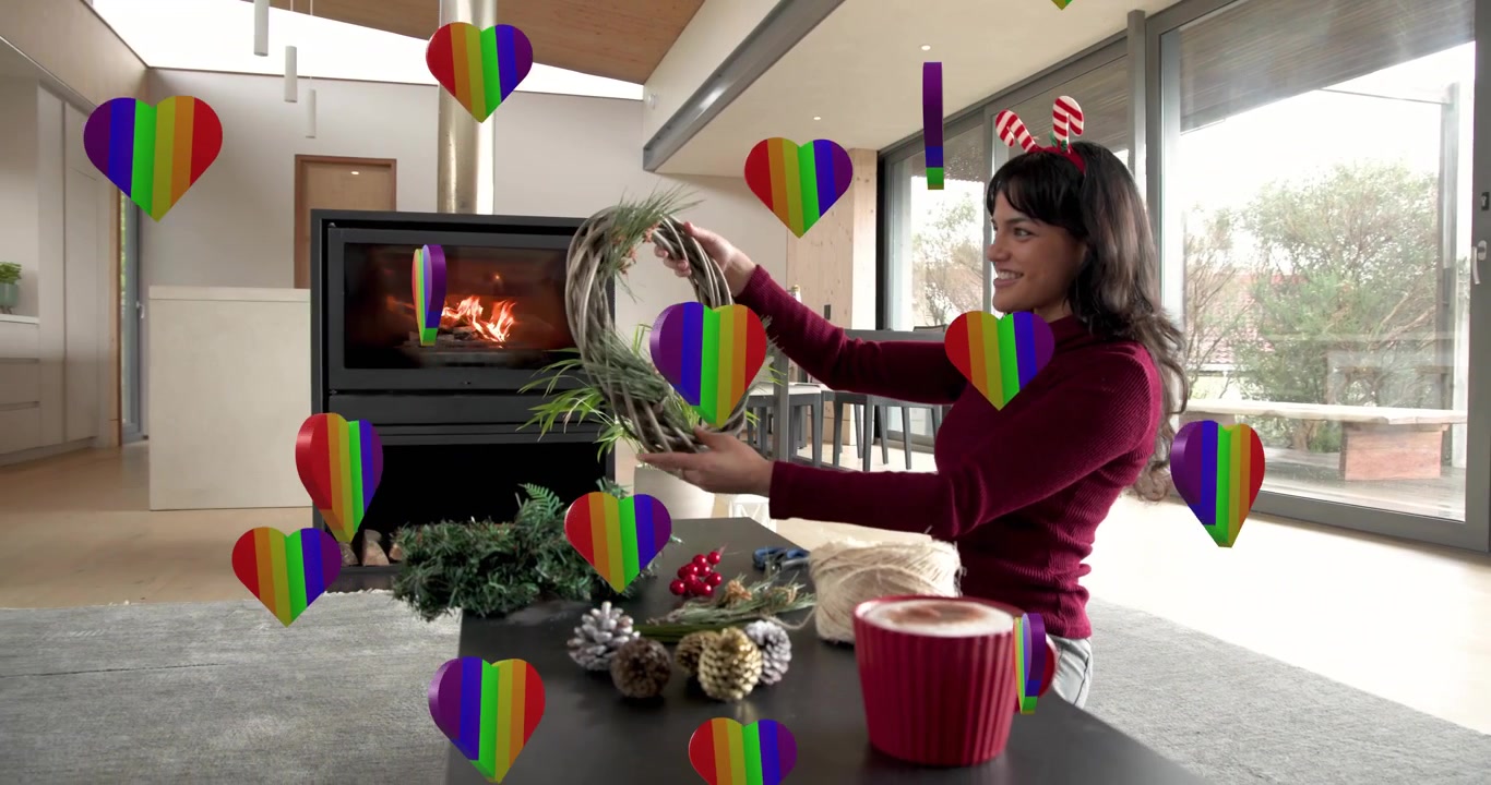 Mulher levantando uma coroa de videira, prendendo galhos com barbante e adicionando pinhas, criando uma guirlanda de Natal.