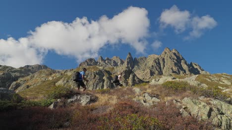 fit couple hiking with walking sticks in rugged mountains on summer day