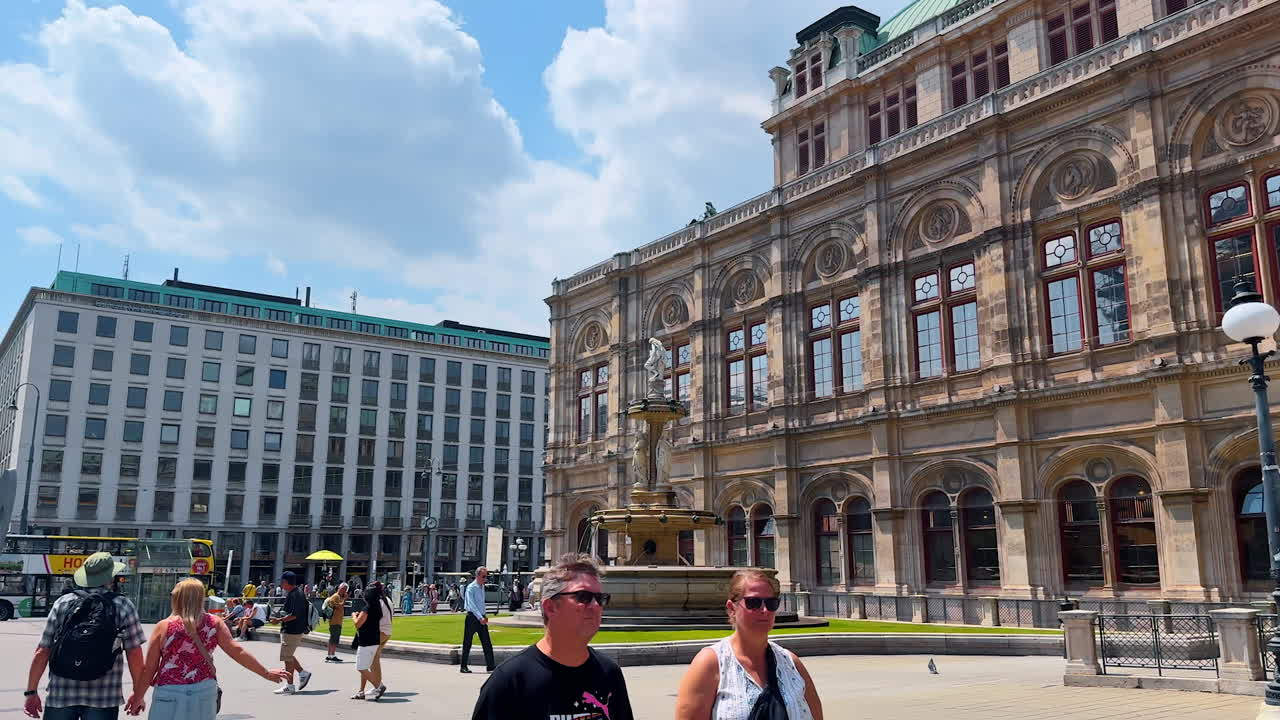 Vienna, Austria - June 9, 2025: Pedestrian walk by the square in front of Vienna State Opera. View on the stunning façade of the beautiful historical building