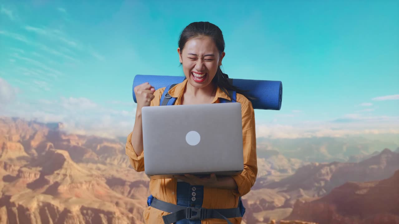 Asian Female Hiker With Mountaineering Backpack Looking At A Laptop And Screaming Goal Celebrating The Success While Traveling At The Top Of Mountain