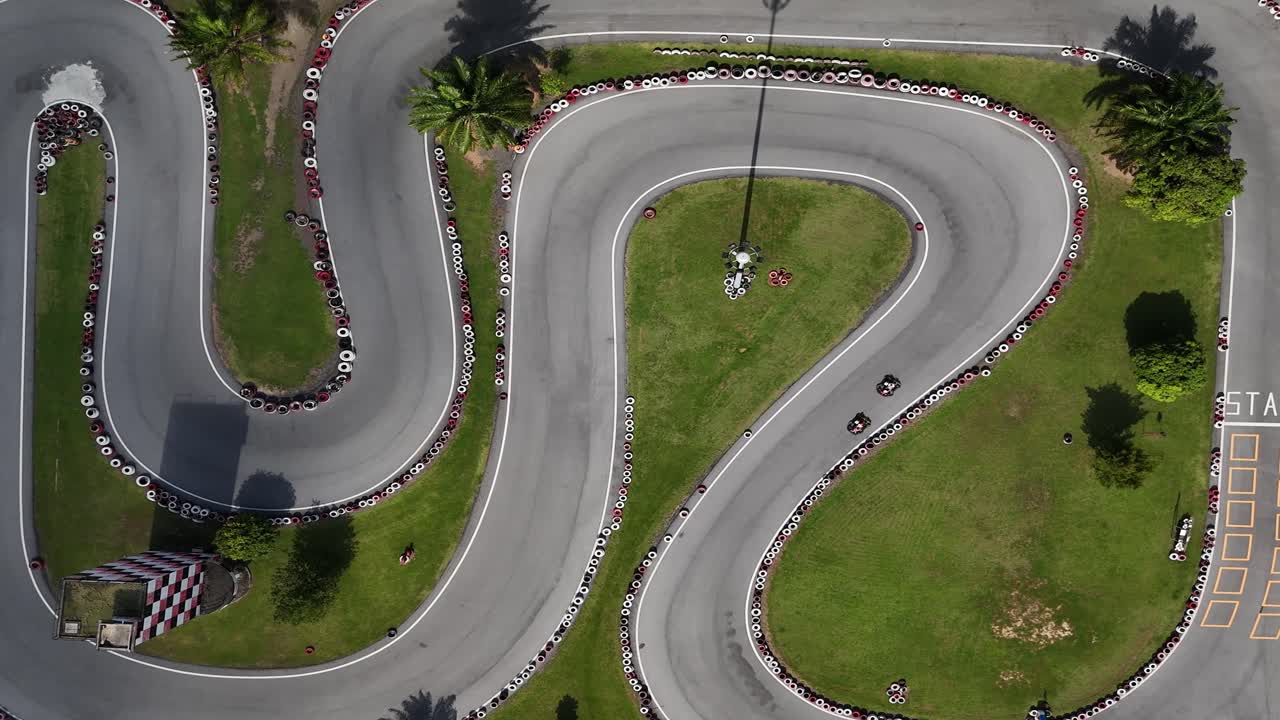 Aerial view of a go-kart track with tire barriers and palm trees