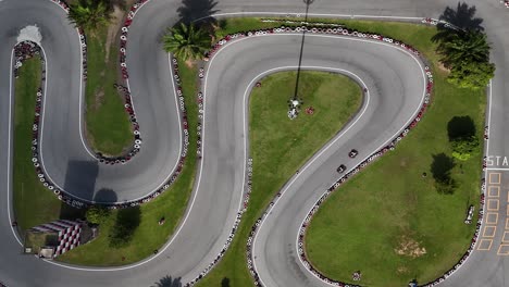 aerial view of a go-kart track with tire barriers and palm trees