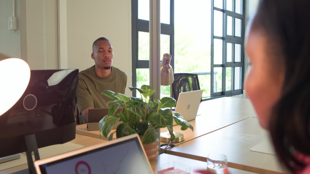 African American coworkers reviewing data, woman pointing at laptop, man laughing and leaning