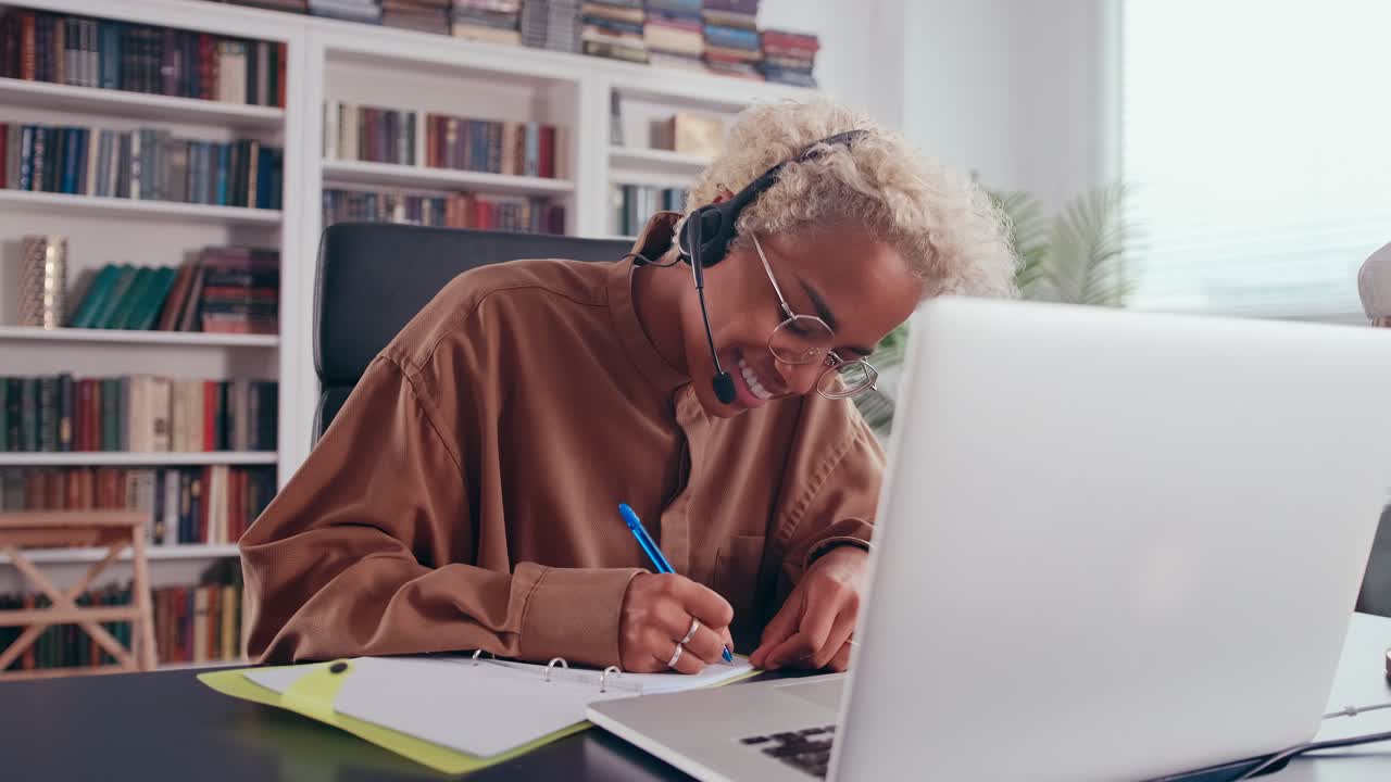 Ung afroamerikansk kvinne jobber og konsulterer folk ved hjelp av headset med mikrofon