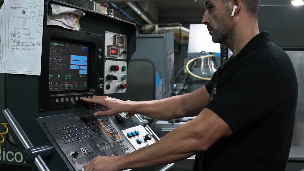 A man operating a CNC machine in a factory
