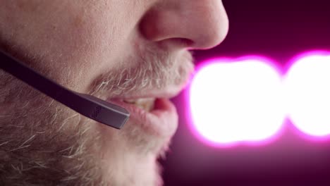 lower face profile close up: man speaks into headset in warm lighting