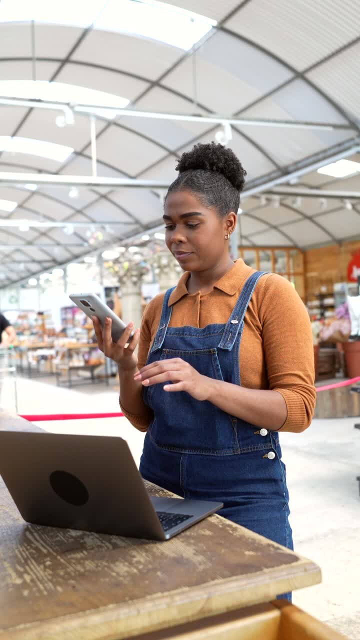 Woman working on laptop and talking on the phone in a greenhouse