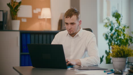 Businessman-using-laptop-at-desk-in-office.