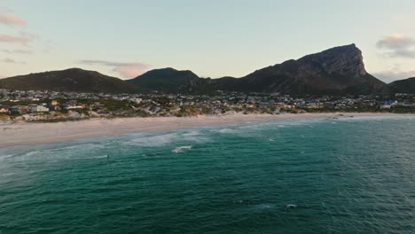 Single-kitesurfer-riding-in-front-of-Pringles-Bay-near-Cape-Town,-far-away-drone-shot