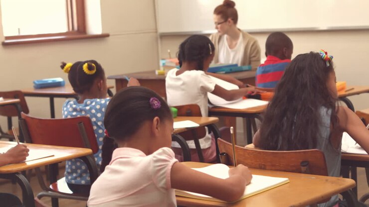Alunos bonitos que escrevem nas mesas da sala de aula