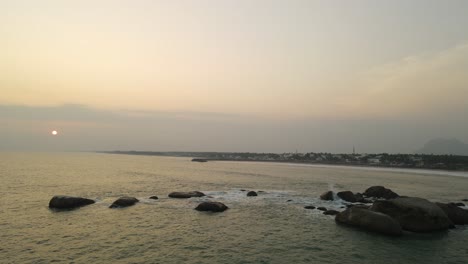 majestic aerial drone shot of kanyakumari with the ocean and city illuminated by the golden hues of sunset.