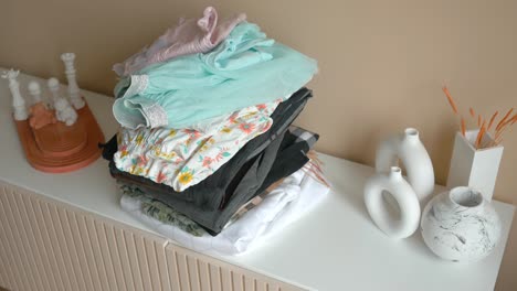 folded clothes stacked on a white shelf