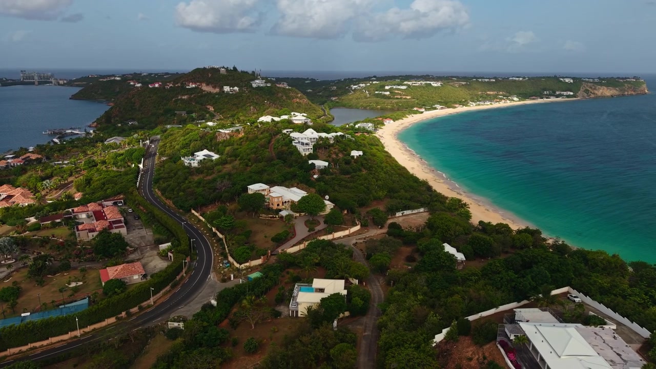 Ripresa con drone della costa dell'isola di St. Martin, colline e case tra la spiaggia di Baie Rouge e la laguna di Simpson Bay.