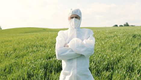 caucasian researcher man in white protective suit and goggles doing pest control in the green field