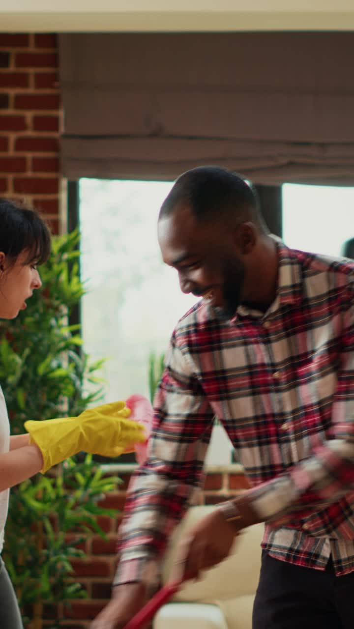 Vertical video: Young man washing dust and dirt off of living room floors