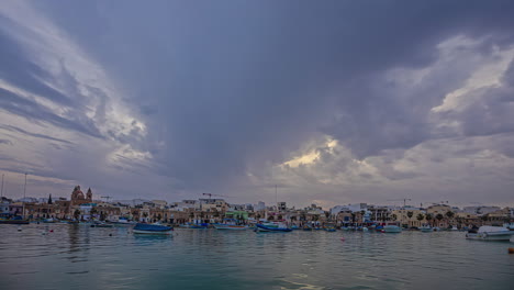 Timelapse-De-Nubes-Nocturnas-Moviéndose-Sobre-Barcos-Amarrados-En-Marsaxlokk,-Malta