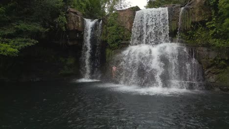 person stands under natural waterfall