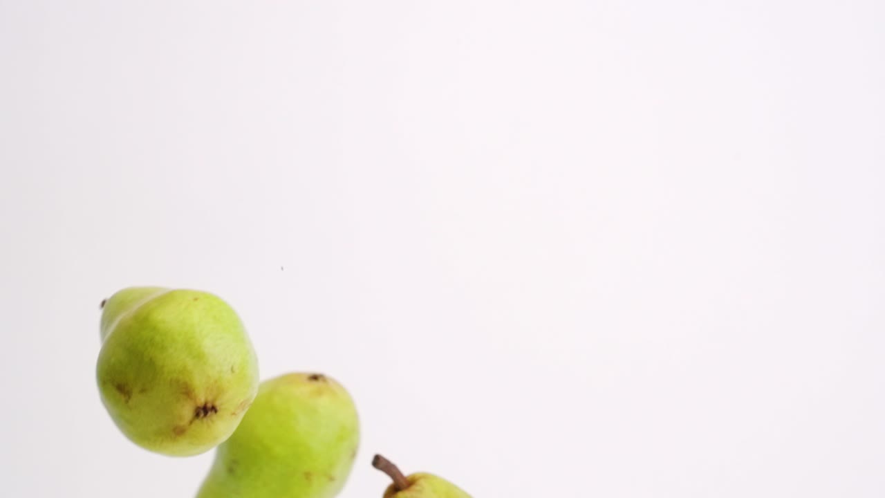 peras enteras cayendo y rebotando en cámara lenta sobre fondo de estudio blanco en 4k