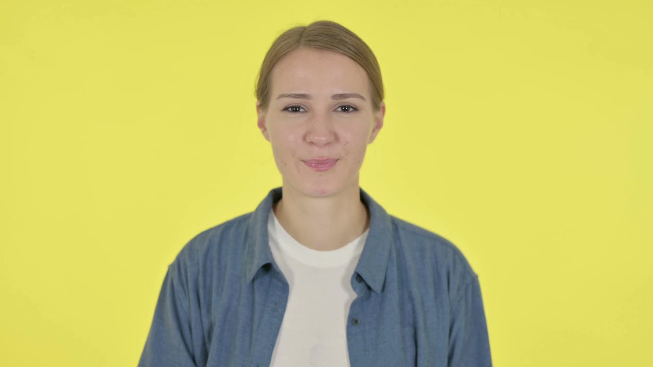 노란색 배경에 은 표지판을 보여주는 젊은 여성