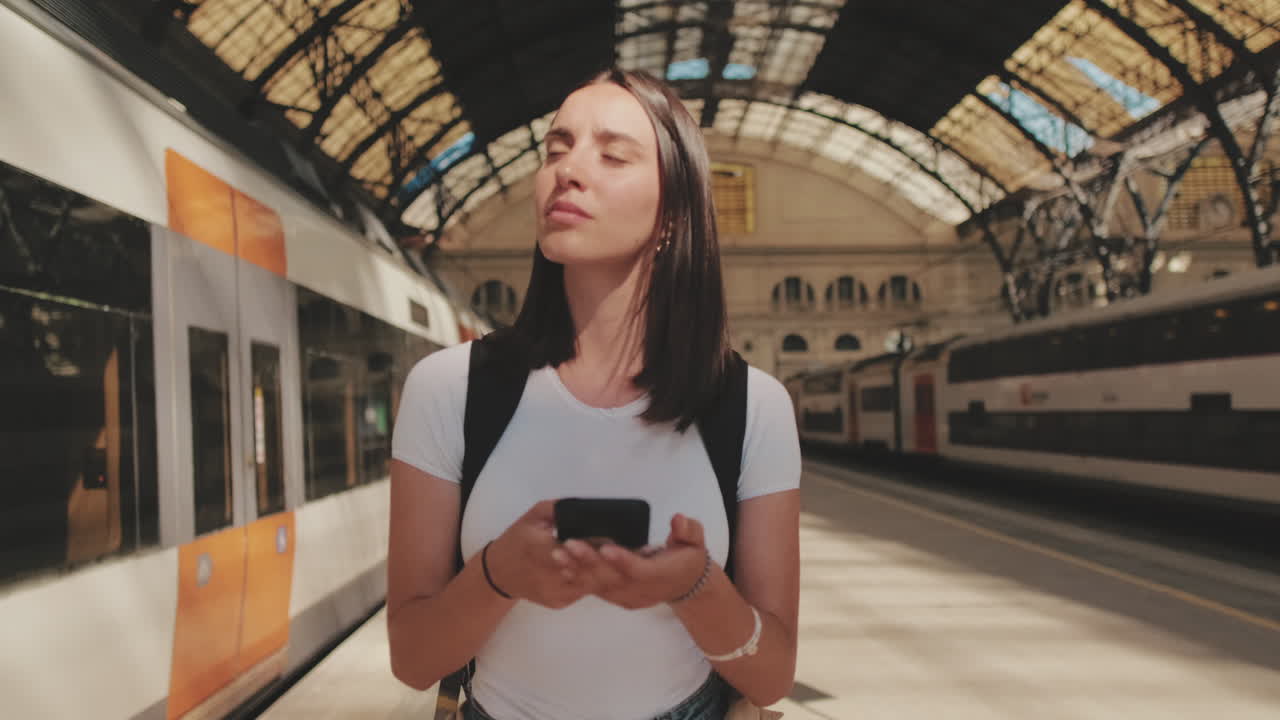 Giovane donna che usa lo smartphone mentre aspetta alla stazione ferroviaria