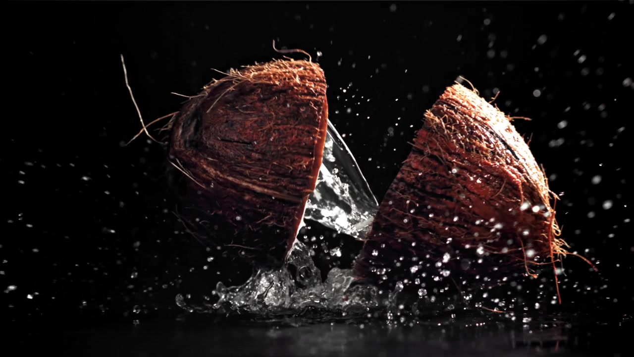 Slow Motion Coconut Breaking with Water Splashing on Black Background