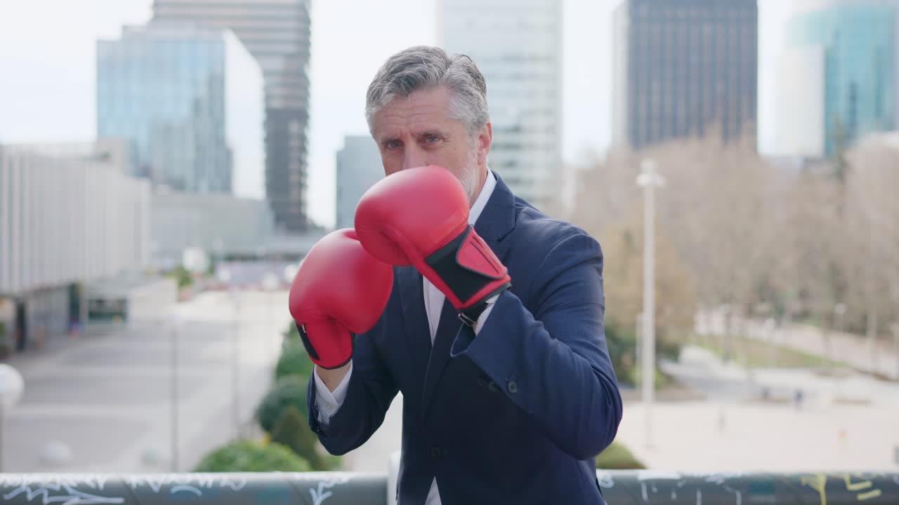 Uomo d'affari con guantoni da boxe rossi in un contesto urbano