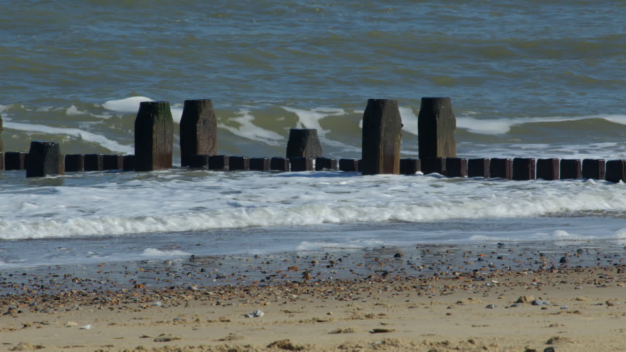close up shot of the waves crashing over the sea defence groynes at Walcott Beach