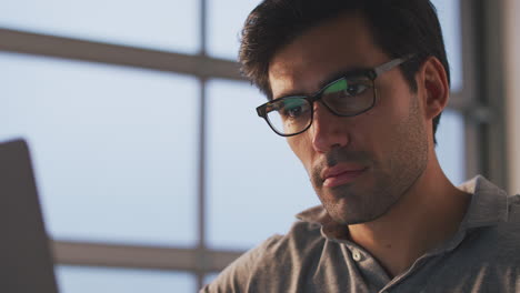 tired businessman working late using laptop at desk in office takes off glasses