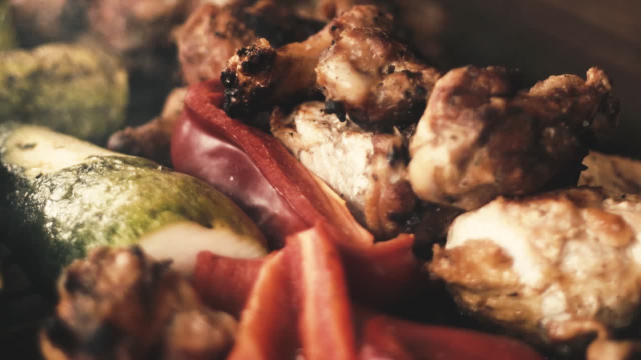 Slow-motion close-up chicken wings and grilled vegetables, (Italian squash and red pepper or red pepper - smoke from the charcoal grill)