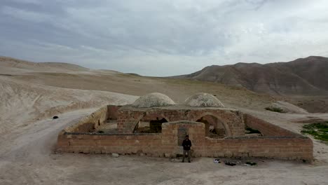 Pull-out-of-man-standing-by-an-ancient-ruin-in-the-Judean-Desert,-Israel