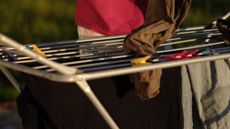 unrecognizable man draping clothes on line during sunset