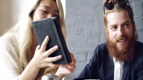 friends hanging out using digital tablet touchscreen in cafe