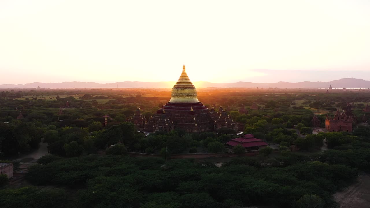 Sorvolando lo splendido paesaggio della campagna del Myanmar, avvicinandosi alla bellissima Pagoda Dhammayazaka giallo dorato al tramonto - Ripresa aerea