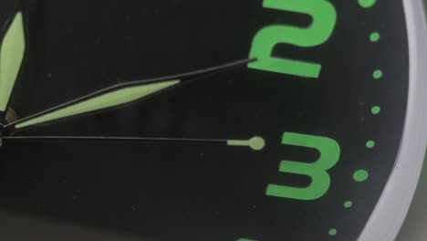 close up on the second hand of a black and green wall clock turning inexorably - symbol, the time flies - macro