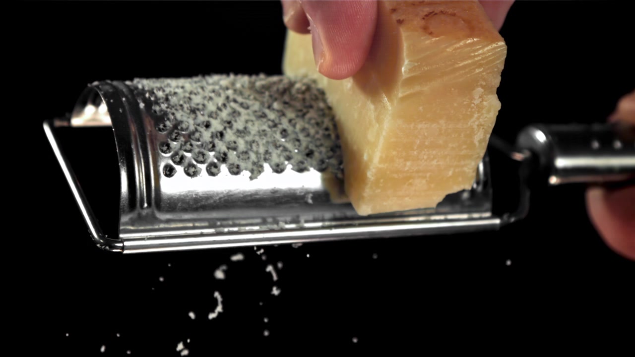Mano che grattugia Parmigiano Reggiano al rallentatore