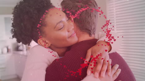 animation of hearts and light spots over diverse couple embracing in kitchen