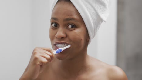 Happy-african-american-woman-brushing-teeth-in-bathroom
