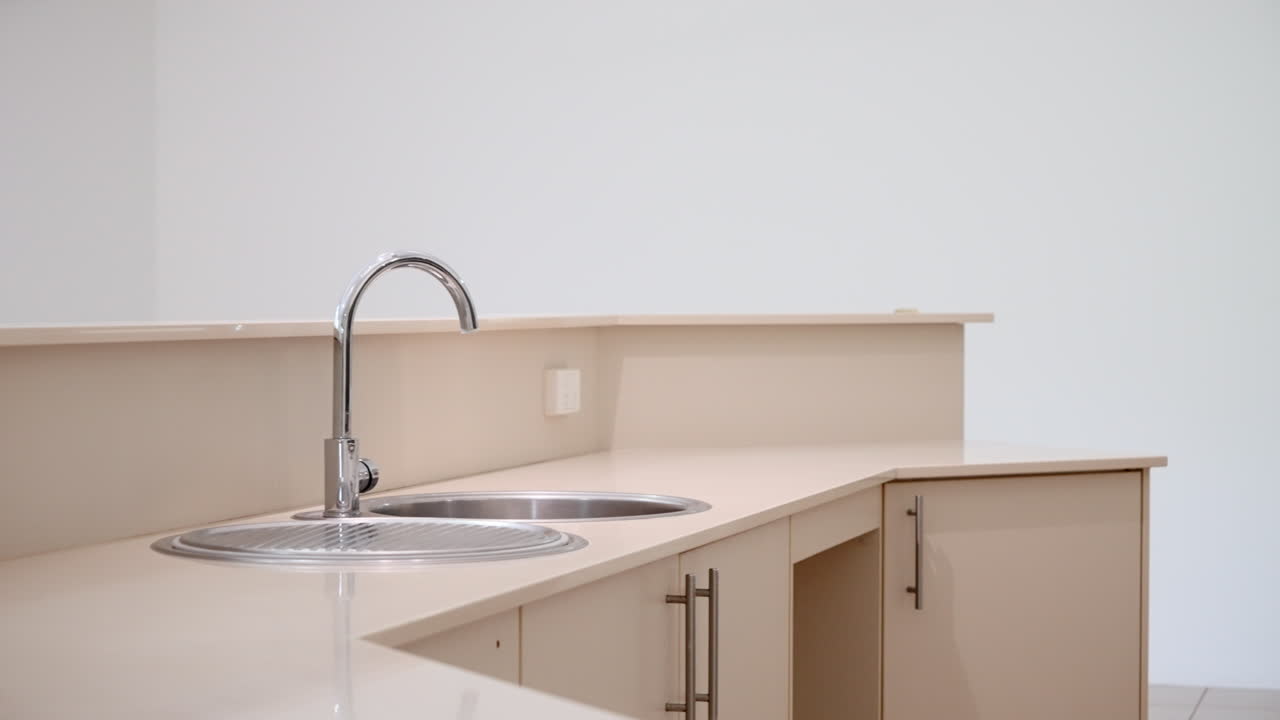 Vacant Empty Large Modern Kitchen Home Interior Close Up Pan Across Sink to Gas Stove With Grey Backsplash. Interior of house for real estate property.