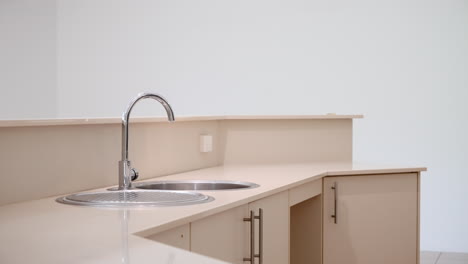 vacant empty large modern kitchen home interior close up pan across sink to gas stove with grey backsplash. interior of house for real estate property.