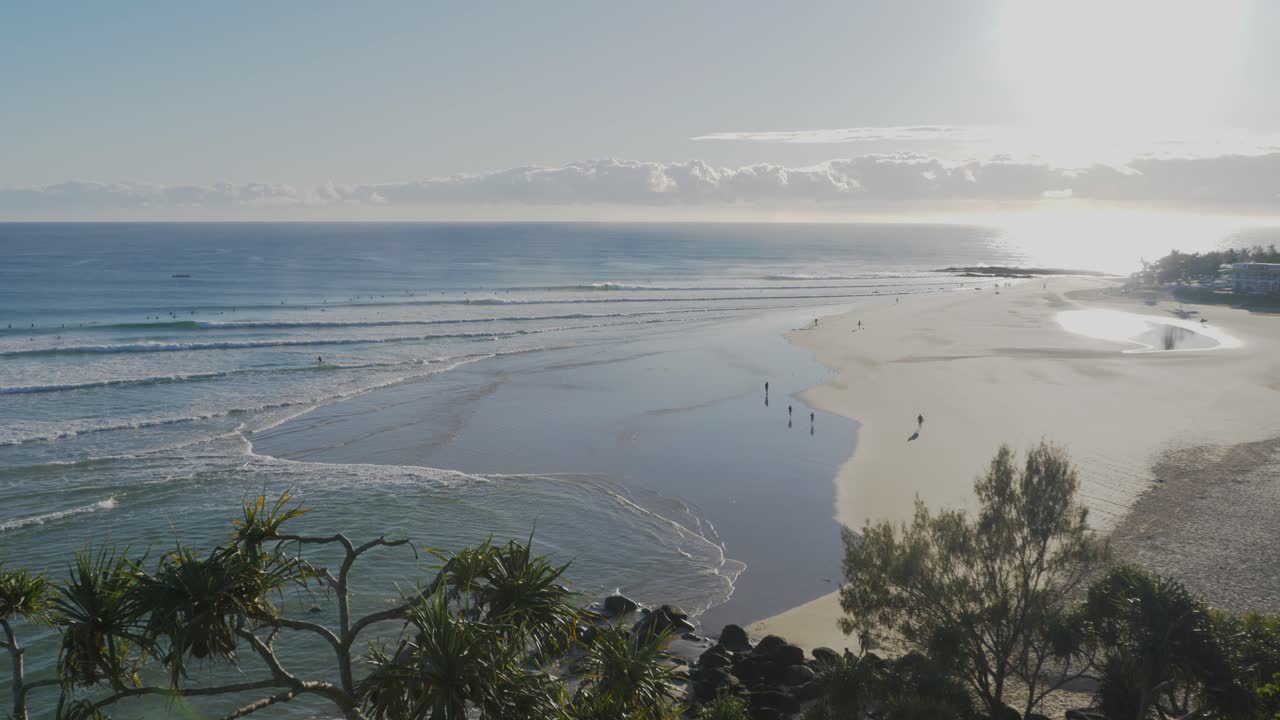 gente caminando en la orilla de la playa de rocas de pargo en un amanecer - olas en el océano azul - bahía del arco iris - costa dorada, queensland, australia