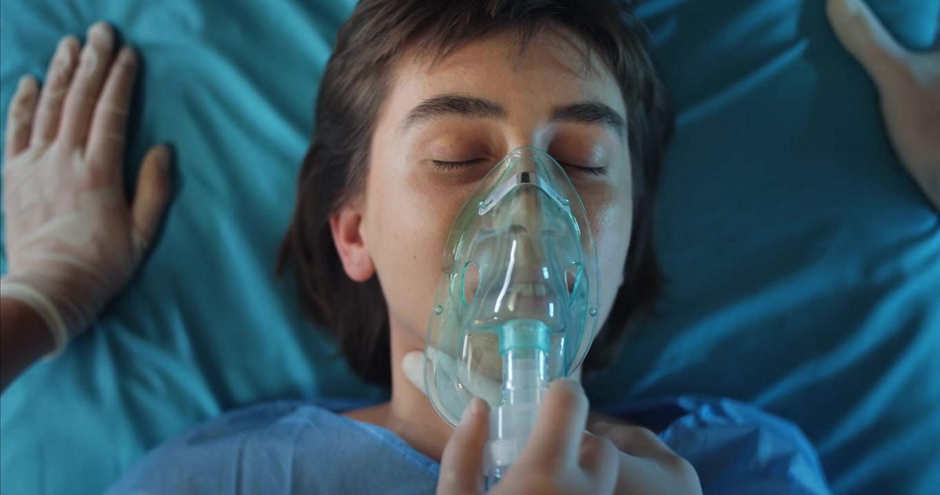 Primer plano de mujer joven respirando con mascarilla de oxígeno en el hospital