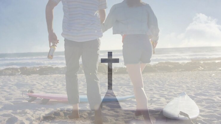 Travel couple holding bottles and glancing, walking beach past surfboards then running toward ocean