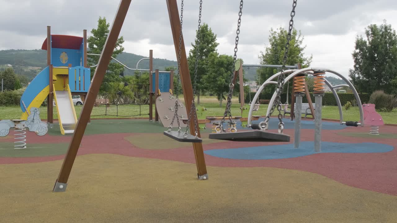 columpios balanceándose en el parque infantil vacío en un día sombrío