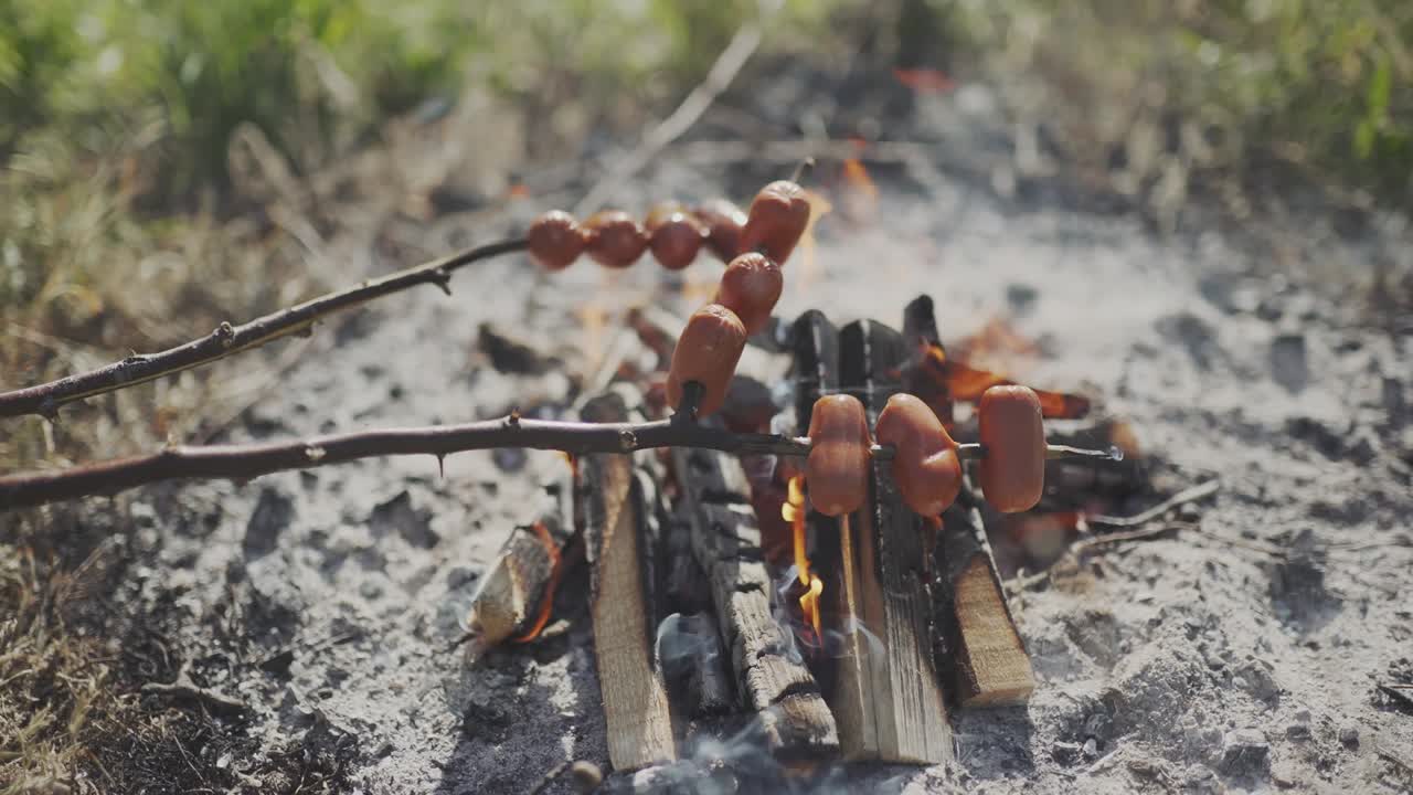 Grelhando salsichas gordurosas na fogueira. Atividade ao ar livre popular na zona rural tcheca. Preparando salsichas junto à fogueira.