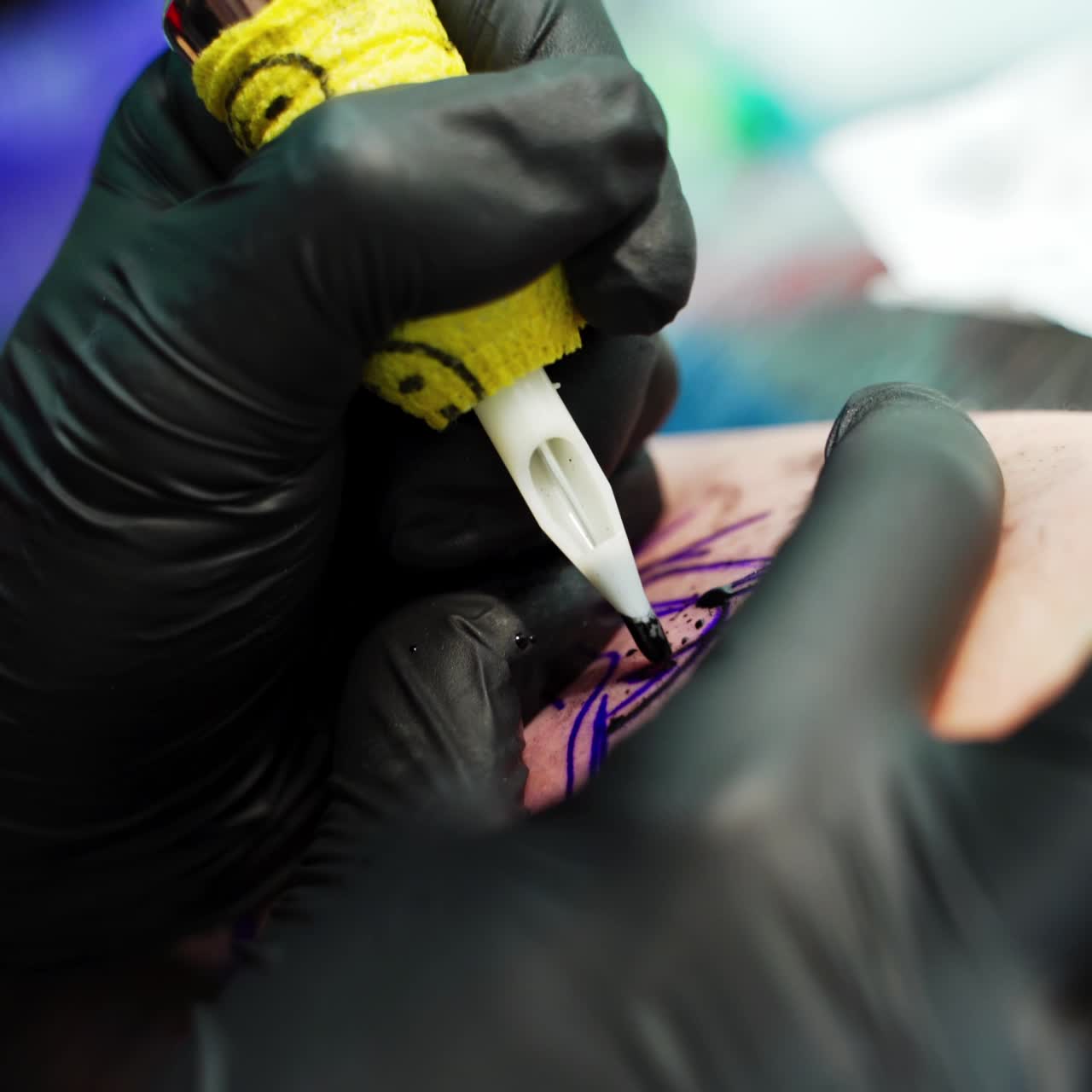 Gloved hands use special machine for tattoos. Putting the tattoo on the hand. Close up