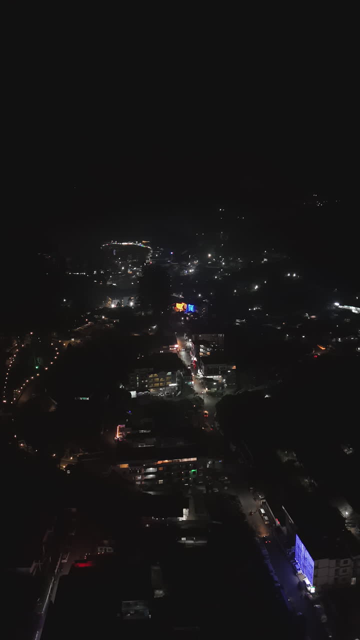 Aerial portrait shot circling illuminated streets of Munnar, night in Kerala, India